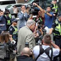 Cardinal George Pell (center) walks along a street in Melbourne, Australia, on Monday. | AFP-JIJI