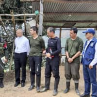 Hostages Carlos Quiceno (fourth, left), Julio Diaz (fourth, right) and Maxwell Joya (third, right) stand next to a representative of the Ombudsman office and the Catholic Church and ELN guerrillas as they are released in Catatumbo, Norte de Santander Department, Colombia, on Sunday. | COLOMBIAN OMBUDSMAN / VIA AFP-JIJI