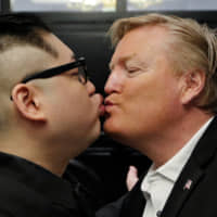 Howard X, an Australian impersonating North Korean leader Kim Jong Un, kisses an impersonator of U.S. President Donald Trump at the La Paix Hotel in Hanoi on Monday. | REUTERS