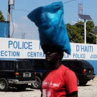 A man carries a bag in front of a main Haitian police station, where according to local media a group of foreign nationals including Americans armed with semi-automatic weapons were detained, after anti-government protests, in Port-au-Prince Monday. | REUTERS