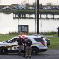 Law enforcement officers man a road block leading to a staging area during the investigation of a plane crash in Trinity Bay in Anahuac, Texas, Saturday. | BRETT COOMER / HOUSTON CHRONICLE / VIA AP