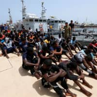 Migrants sit at a naval base after being rescued by Libyan coast guard elements in Tripoli last July. | REUTERS