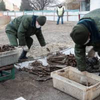 Soldiers from a special \"search battalion\" of the Belarus Defense Ministry collect the remains of about 730 prisoners of a former Jewish ghetto, discovered in a mass grave at a construction site in the center of Brest, Belarus, Tuesday. | REUTERS