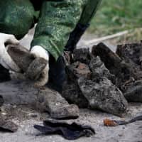A soldier from a special \"search battalion\" of the Belarus Defense Ministry takes part in the exhumation of a mass grave containing the remains of about 730 prisoners of a former Jewish ghetto, discovered at a construction site in the center of Brest, Belarus, Tuesday. | REUTERS