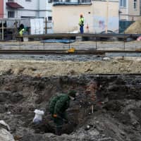 A soldier from a special \"search battalion\" of the Belarus Defense Ministry takes part in the exhumation of a mass grave containing the remains of about 730 prisoners of a former Jewish ghetto, at a construction site in Brest, Belarus, Tuesday. | REUTERS