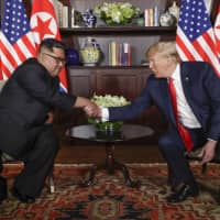 North Korea leader Kim Jong Un and U.S. President Donald Trump shake hands during their first meeting at the Capella resort on Sentosa Island in Singapore on June 12. | AP
