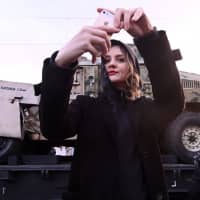 A woman takes a selfie as she attends a mobile exhibition installed on freight cars of a train and displaying military equipment, vehicles and weapons, which, according to Russia\'s Defense Ministry, were captured during its Syrian campaigns, upon its arrival at a railway station in Rostov-on Don, Russia, Wednesday. | REUTERS