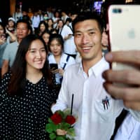 Thanathorn Juangroongruangkit, leader of the Future Forward Party, takes a selfie with his supporters during a campaign rally in Bangkok on Feb. 20. | REUTERS