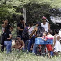 Venezuelan migrants rest under a tree near the International bridge Tienditas, on the outskirts of Cucuta, Colombia, on the border with Venezuela Tuesday. Venezuelan opposition leader Juan Guaido is moving ahead with plans to try to bring in humanitarian aid through the Colombian border city of Cucuta, where the U.S. government will transport and store food and medical supplies destined for Venezuela. | AP