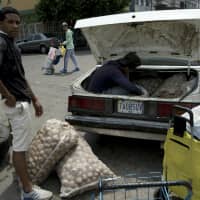 A man loads his car with potatoes bought in Colombia, in San Antonio del Tachira, Venezuela, on the border with Colombia, Thursday. Opposition leaders led by self-proclaimed interim president Juan Guaido are vowing to bring in U.S. supplies of emergency food and medicine to dramatize the country\'s hardships under President Nicolas Maduro, who has said the country doesn\'t need such help. | AP