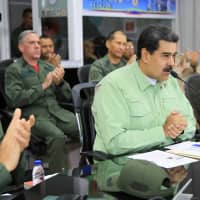 Venezuelan President Nicolas Maduro is accompanied by the military high command during a special broadcast at Tiuna Fort in Caracas Thursday. Maduro said Venezuela would shut its border with Brazil on Thursday \"until further notice\" amid a tense standoff with opposition leader Juan Guaido over allowing in humanitarian aid. | VENEZUELAN PRESIDENCY / VIA AFP-JIJI