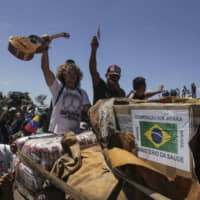 Venezuelans surround the first truck with humanitarian aid from the Brazilian government as it arrives in Pacaraima, Brazil, on Saturday. | AP