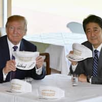 U.S. President Donald Trump and Prime Minister Shinzo Abe pose for photographs with autographed hats reading \"Donald and Shinzo, Make Alliance Even Greater\" at Kasumigaseki Country Club in Kawagoe, Saitama Prefecture in November 2017. | BLOOMBERG