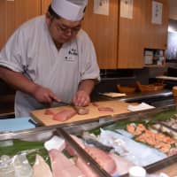 A sushi chef slices pieces of bluefin tuna that was aged with an aging sheet at a Uogashi Nihonichi restaurant in Kawasaki on Jan. 16. | SATOKO KAWASAKI