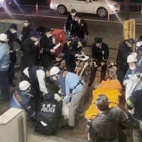 Police officers and ambulance staff are seen at the site of a knife attack where two people were injured on a street near Korakuen Station in Bunkyo Ward, Tokyo, on Thursday. | KYODO