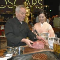 Wolfgang Puck (left), an Austrian-American chef who has catered the official Oscars after-party for 25 years, examines a slab of Miyazaki wagyu beef during a preview event Friday in Hollywood. | KYODO
