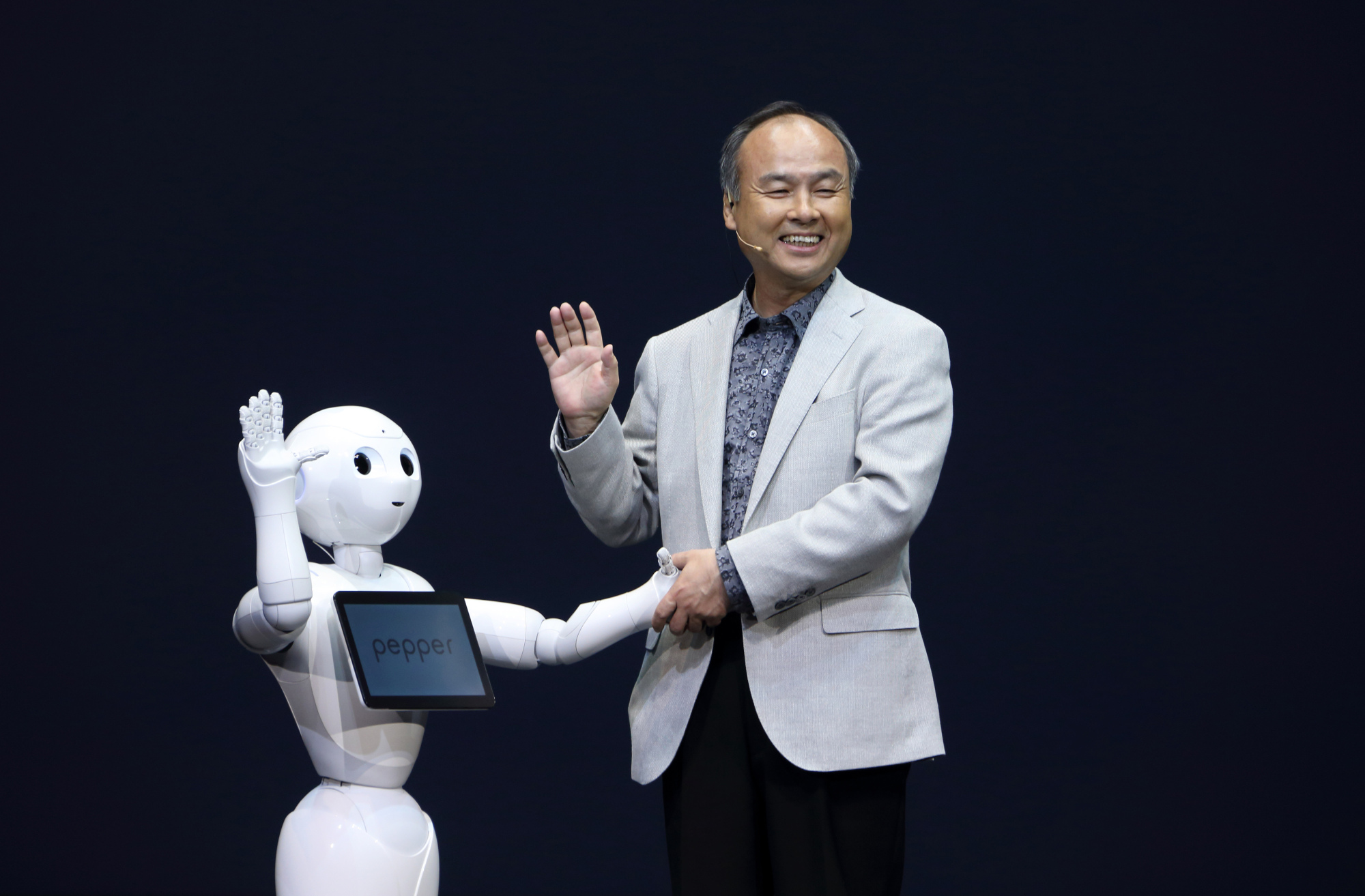 SoftBank Corp. Chairman Masayoshi Son greets the company's Pepper robot during a news conference in Urayasu, Chiba Prefecture, in June 2014. | BLOOMBERG