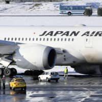 A Japan Airlines Co. plane is seen with its left main landing gear off the runway Friday morning at Narita Airport. The airport briefly closed one of its two runways due to the incident. | KYODO