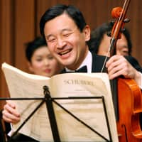 Crown Prince Naruhito laughs as he prepares to play the viola during a photo session before a friendship concert with famous Asian artists in Tokyo in January 2007. | AP