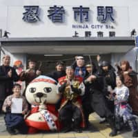 Sakae Okamoto (center), mayor of Iga, Mie Prefecture, poses as a ninja with others on Friday, locally designated as \"Ninja Day,\" in front of a train station nicknamed \"Ninja City Station.\" | KYODO