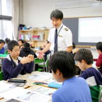 An All Nippon Airways captain talks to elementary school students in Tokyo in October 2017, in an effort to boost the pool of future pilots ahead of an expected shortage. | KYODO