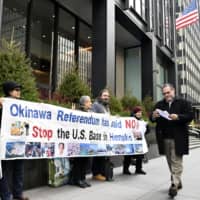 People opposed to a plan to relocate U.S. Marine Corps Air Station Futenma to the Henoko area of Nago, Okinawa Prefecture, hold a rally outside the Japanese Consulate in New York on Monday. | KYODO