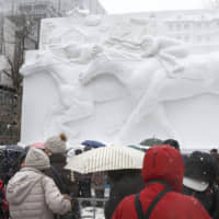 Visitors view a snow sculpture of thoroughbred horses at the annual Sapporo Snow Festival in Hokkaido on Feb. 4. | KYODO