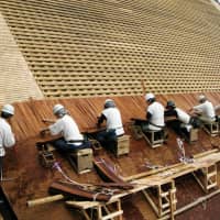 A handout photo shows craftsmen placing Japanese cypress bark shingles on a roof, an example of traditional Japanese architectural techniques that the government is planning to nominate for addition to UNESCO\'s Intangible Cultural Heritage list. | KYODO