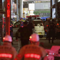 Police officers examine a car that rammed into pedestrians on Takeshita Street in Tokyo\'s Harajuku district in the early hours of New Year\'s Day. | AP