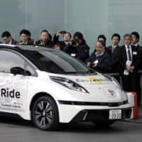 Journalists photograph a Nissan Leaf electric vehicle operated by the Easy Ride robot taxi service, a joint development between Nissan Motor Co. and DeNA Co., during a demonstration in Yokohama on Feb. 23, 2018. | BLOOMBERG