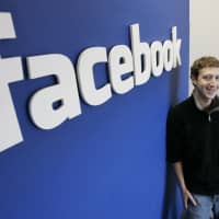 Mark Zuckerberg poses for a photo next to a Facebook logo at the offices in Palo Alto, Calif., on Feb. 5, 2005. The social networking site turned 15 on Monday. | AP