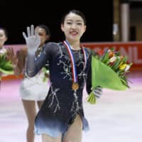 Challenge Cup champion Rika Kihira (front) leads second-place finisher Starr Andrews (center) and Wakaba Higuchi, who placed third, around the rink following the competition on Sunday in The Hague, Netherlands. | KYODO