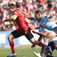 The Sunwolves\' Gehrard van den Heever is tackled by Israel Folau and another Waratahs player Saturday. | KYODO