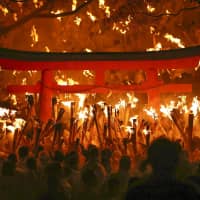 Hundreds of men hold up torches at Kamikura Shrine in Shingu, Wakayama Prefecture, on Wednesday during Oto Matsuri (Torch Festival), which dates back 1,400 years. About 1,700 participants, all in white costumes, lit their torches from sacred fire and ran down 538 stone steps from the top of Mount Kamikura to make a wish. | KYODO