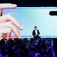Richard Yu, CEO of the Huawei Consumer Business Group, unveils the new Huawei P30 and P30 Pro smartphones during a launch event in Paris Tuesday. | REUTERS