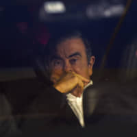 Former Nissan Chairman Carlos Ghosn leaves his lawyers\' office in a car Wednesday after he was released from the Tokyo Detention House on bail earlier in the day. | AFP-JIJI