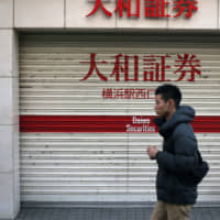 Pedestrians walk past a Daiwa Securities Co. branch in Yokohama. Daiwa and other brokerages are taking steps to alleviate worries over a market shutdown during an unusually long 10-day holiday related to the Emperor\'s succession. | BLOOMBERG