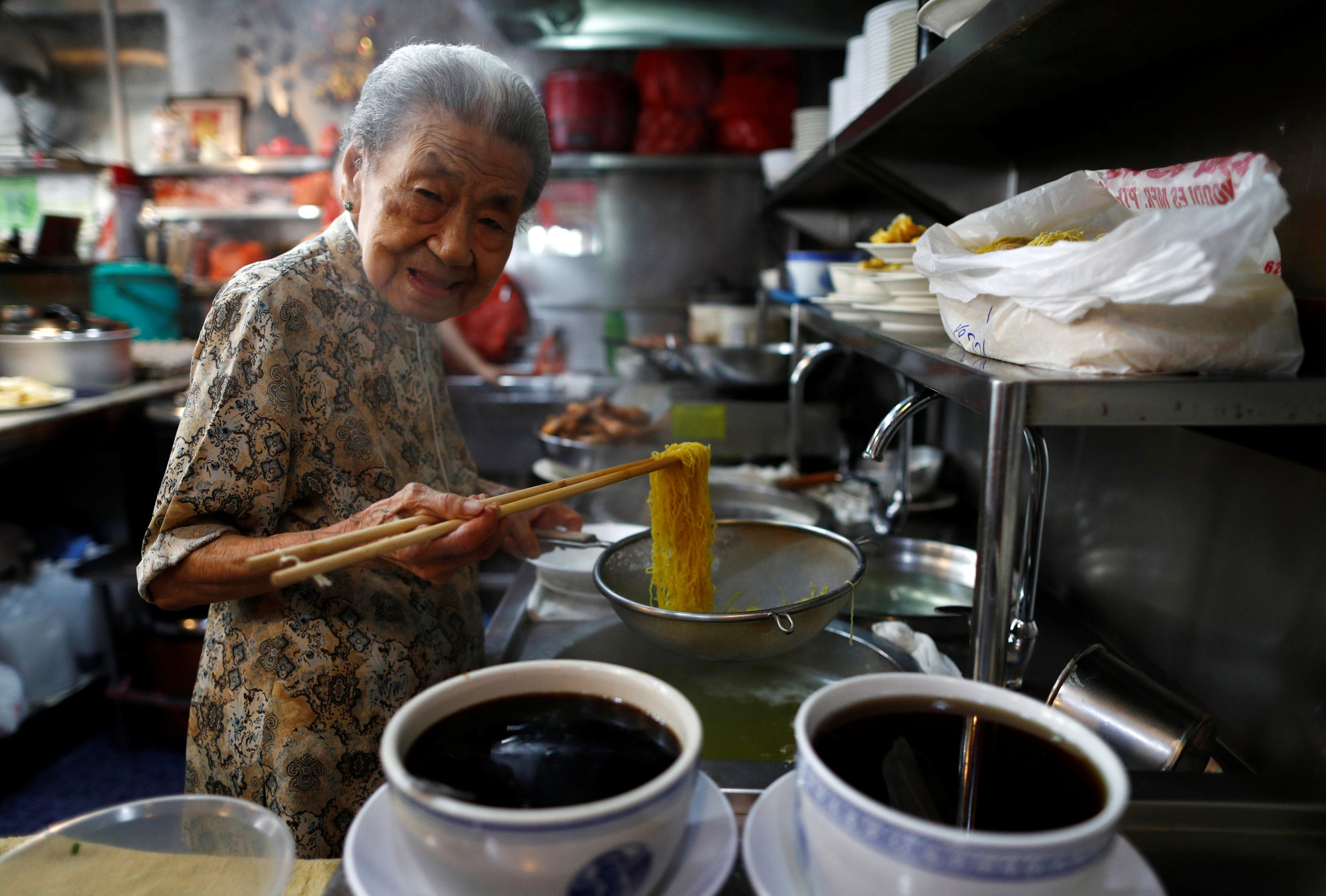 Hawker Leong Yuet Meng, 90, of Nam Seng Noodle House, cooks noodles at her shop in Singapore Feb. 22. | REUTERS