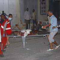 Somalis help a wounded person after a car bombing in Mogadishu Thursday. | AP