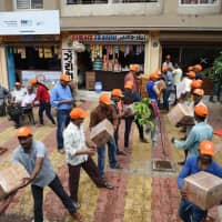 Indian volunteers from the Haridwar Mitra Mandal Charitable Trust load aid packets to be shipped to flood-hit Kerala, in Ahmedabad, on August 19. | AFP-JIJI