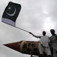 A Pakistani supporter of the Jamaat-e-Islami party holds a Pakistan national flag beside a replica of a missile during an anti-Indian protest rally in Karachi on Thursday. | AFP-JIJI