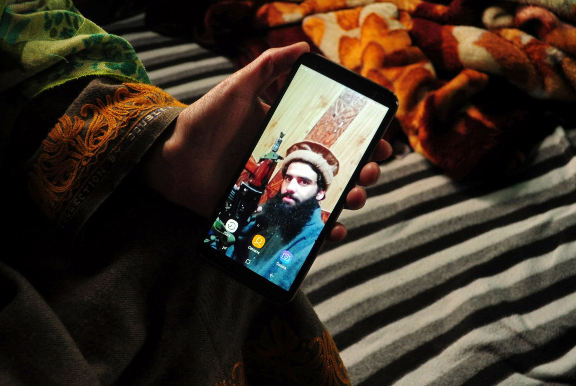 A sister of suspected militant Owais Malik shows a picture of him on her phone at her home in Kashmir's Kulgam district on Feb. 16. | REUTERS