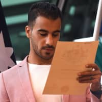 Hakeem al-Araibi reads his Australian citizenship certificate after a ceremony in Melbourne on Tuesday. | AFP-JIJI