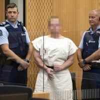 Australian Brenton Tarrant, charged in relation to the massacre at two mosques in Christchurch, makes a sign to the camera during his appearance in the Christchurch District Court on Saturday. | AFP-JIJI