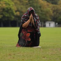 A mourner pays her respects outside the Masjid Al Noor mosque in Christchurch, New Zealand, Monday,. A steady stream of mourners paid tribute at a makeshift memorial to the 50 people slain by a gunman at two mosques in Christchurch, while dozens of Muslims stood by to bury the dead when authorities finally release the victims\' bodies. | AP