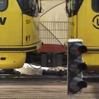 The body of one of three slaying victims is covered with a white sheet as it lies next to a tram after a shooting incident in Utrecht, Netherlands, Monday. A gunman killed three people and wounded nine others on a tram in the central Dutch city of Utrecht, sparking a manhunt that saw heavily armed officers with sniffer dogs zero in on an apartment building close to the shooting. | AP