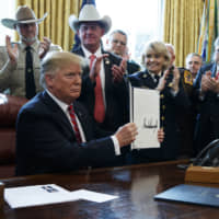 U.S. President Donald Trump shows the first veto of his presidency in the White House on Friday. | AP