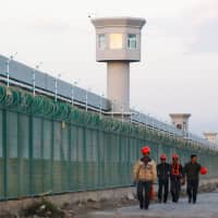Workers walk by the perimeter fence of what is officially known as a vocational skills education center in Dabancheng, in Xinjiang Uighur Autonomous Region, China, on Sept. 4. | REUTERS