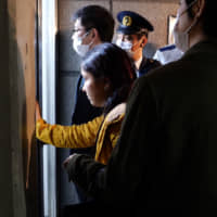 Yasemin Colak, the wife of Kurdish detainee Mehmet Colak, tries to see what\'s happening inside the Tokyo Regional Immigration Bureau in Minato Ward after an ambulance crew entered the building to check on her husband\'s condition on the evening of March 12. | CHISATO TANAKA
