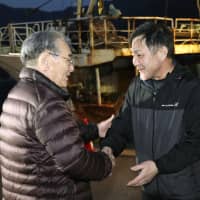 Hideji Kagami (right), the captain of the Nishino Maru No. 68 crab-fishing boat, is welcomed home after arriving at a port in Sakaiminato, Tottori Prefecture, on Sunday. The boat was detained by Russian authorities in late January for allegedly illegally fishing. | KYODO